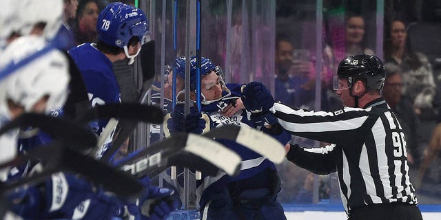 Linesman Dan Kelly, #98, pushes Toronto Maple Leafs left wing Michael Bunting, #58, off the ice at the end of the period after a roughing incident as the Toronto Maple Leafs play the Tampa Bay Lightning at Scotiabank Arena in Toronto. Dec. 20, 2022.        