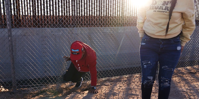 Migrants illegally cross into the United States via a hole in a fence in El Paso, Texas, on Dec. 22, 2022. 