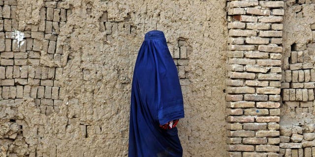 TOPSHOT - An Afghan burqa-clad woman walks through a street in Kandahar on December 25, 2022. 