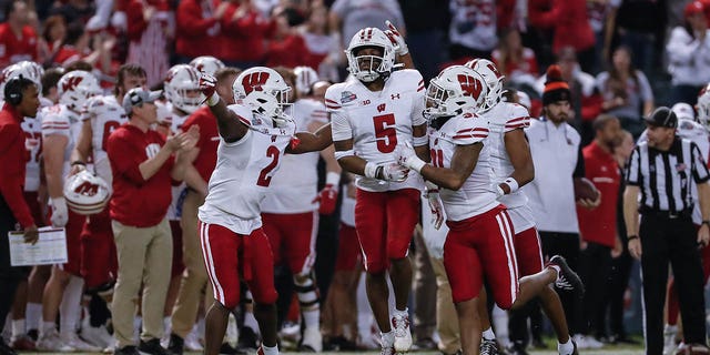 Wisconsin Badgers cornerback Cedrick Dort Jr., #5, celebrates an interception with teammates during the college football Guaranteed Rate Bowl game between the Wisconsin Badgers and the Oklahoma State Cowboys on Dec. 27, 2022 at Chase Field in Phoenix.