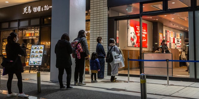 Oamenii se aliniază în fața unui KFC pe 23 decembrie 2020 în Tokyo, Japonia.