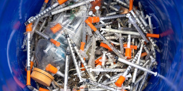 This file image shows heroin syringes fill a bucket after volunteers collected them at a homeless encampment on March 1, 2022 in Seattle, Washington. 
