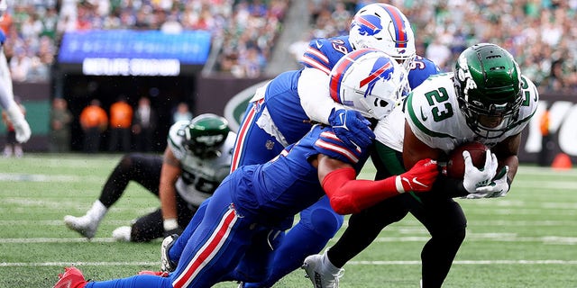 James Robinson (23) of the New York Jets runs for a touchdown as Tim Settle (99) and Damar Hamlin (3) of the Buffalo Bills tackle him in the third quarter at MetLife Stadium on November 6, 2022 in East Rutherford, NJ 