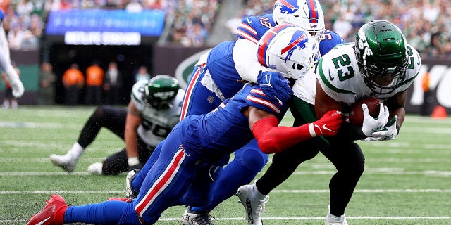 James Robinson (23) of the New York Jets runs for a touchdown as Tim Settle (99) and Damar Hamlin (3) of the Buffalo Bills tackle him in the third quarter at MetLife Stadium Nov. 6, 2022, in East Rutherford, N.J.