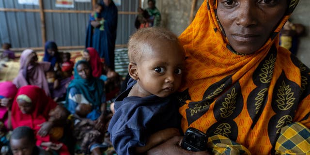 BAIDOA, SOMALIA - NOVEMBER 9: Malnourished Somali baby Adan Macalin Ali, 1, is held by his mother, Hawo Abdi Adan, after being measured at the Danwadaag Mother and Child Health Center, as Somalis struggle to cope with famine conditions due to four failed rainy seasons in a row, and conflict with Islamist Al Qaeda-linked Al-Shabaab rebels, on November 9, 2022 in Baidoa, Somalia. As numbers in need have surged, United Nations and Western relief agencies are warning of famine to come, if there is not an immediate boost of assistance to affected areas. Drought and insecurity have caused the failure of crops and the death of countless camels, cows, and goats, the backbone of this pastoralist economy, resulting in the doubling of displaced people in Baidoa from Al- Shabaab-controlled areas since spring to some 900,000, all in need of food, water and sanitation. (Photo by Scott Peterson/Getty Images)