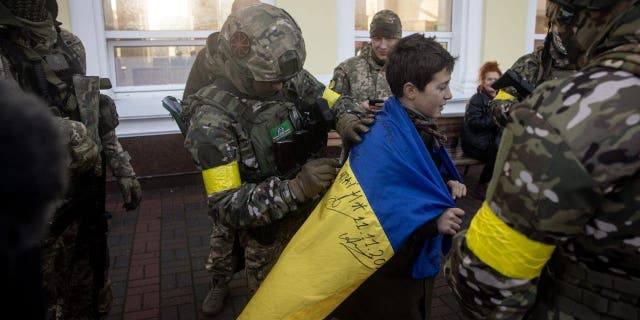 Ein Junge hält die ukrainische Nationalflagge, die am 19. November 2022 in Cherson, Ukraine, von Angehörigen des ukrainischen Militärs unterzeichnet wurde.