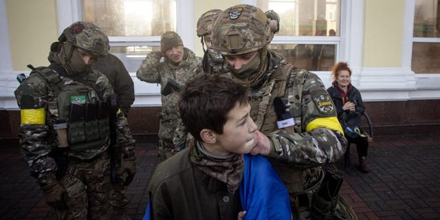 A boy has his Ukraine national flag signed by members of the Ukrainian military, Nov. 19, 2022, in Kherson, Ukraine.