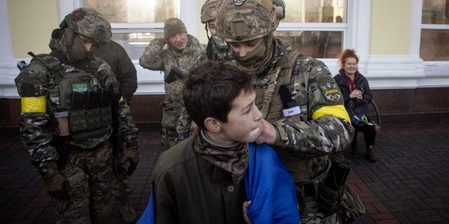 A boy has his Ukraine national flag signed by members of the Ukrainian military, Nov. 19, 2022, in Kherson, Ukraine.