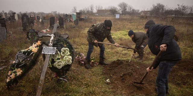 Ukrainische Einwohner und Behörden exhumieren die Leichen eines 16-jährigen Mädchens und sieben Jungen, die am 29. November 2022 in der Stadt Pravdyn, einem Vorort von Cherson, von russischen Streitkräften getötet wurden.