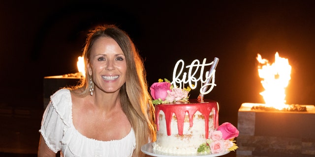Trista Sutter was seen posing next to a pink and white cake with flowers, topped with a sparkler and a birthday sign that read ‘fifty’ in cursive.