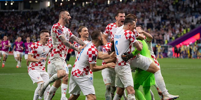 Croatian players celebrate with goalkeeper Dominik Livakovic after saving three penalties in a shootout during the FIFA World Cup Qatar 2022 Round of 16 match between Japan and Croatia at Al Janoub Stadium on December 5, 2022 in Al Wakrah, Qatar. 
