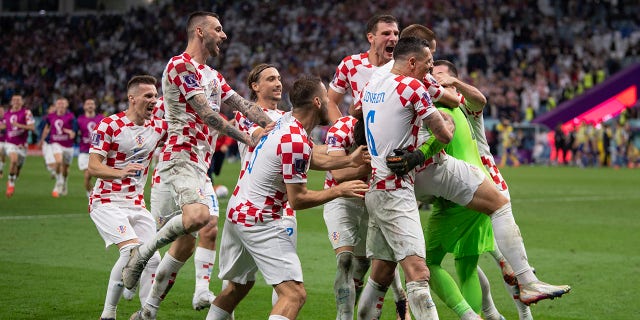 Croatia players celebrate with goalkeeper Dominik Livaković after he saved three penalties in the shootout against Japan during the World Cup match at Al Janoub Stadium on Dec. 5, 2022, in Al Wakrah, Qatar.