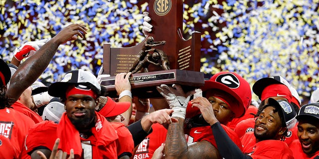 Members of the Georgia Bulldogs hoist the SEC championship trophy after their 50-30 victory over the LSU Tigers in the SEC championship game at Mercedes-Benz Stadium Dec. 3, 2022, in Atlanta. 