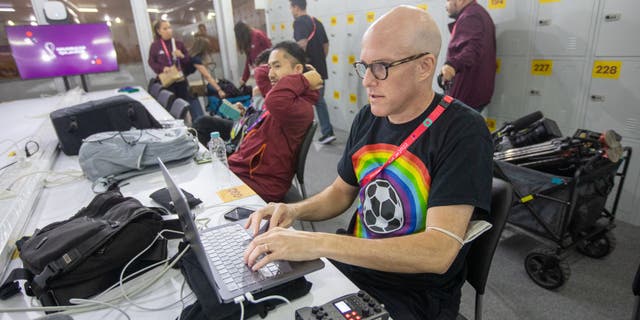 Journalist Grant Wahl (right) works in the FIFA Media Center before a FIFA World Cup Qatar 2022 Group B match between Wales and the United States at Ahmad Bin Ali Stadium on Nov. 21, 2022 in Al Rayyan, Qatar. He had been detained earlier by stadium security for wearing a rainbow-colored T-shirt before later being allowed to enter the stadium.