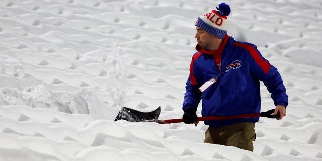 Stadium workers clear snow off the field prior to a game between the Miami Dolphins and Buffalo Bills at Highmark Stadium on Dec. 17, 2022 in Orchard Park, New York.
