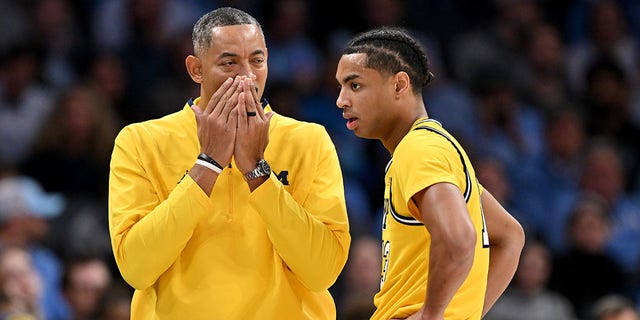 Michigan Wolverines head coach Juwan Howard talks with Jett Howard during the second half of their game against the North Carolina Tar Heels at Spectrum Center in Charlotte, North Carolina, on Wednesday.
