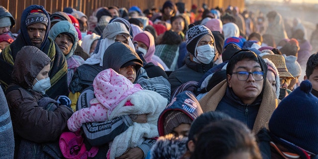 Immigrants bundle up against the cold after spending the night camped alongside the US-Mexico border fence on December 22, 2022 in El Paso, Texas. 