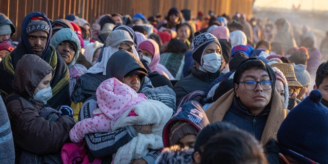 Immigrants bundle up against the cold after spending the night camped alongside the U.S.-Mexico border fence on December 22, 2022 in El Paso, Texas. 