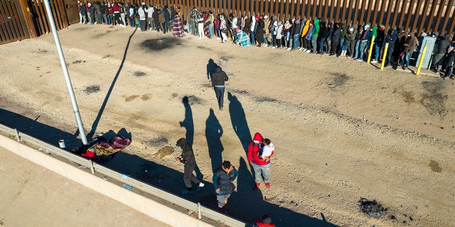 Una vista aérea de inmigrantes haciendo cola junto a la valla fronteriza entre Estados Unidos y México después de pasar la noche afuera el 22 de diciembre de 2022 en El Paso, Texas.