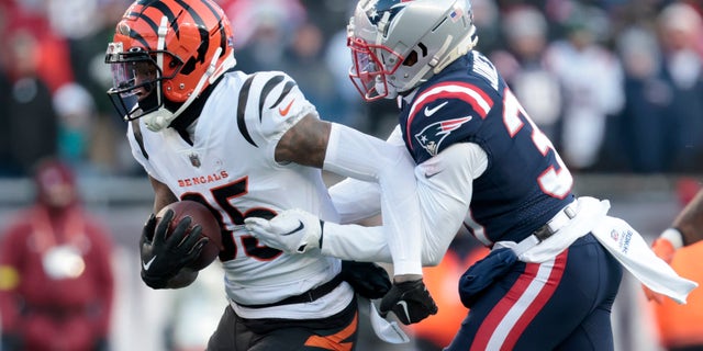 FOXBOROUGH, MASSACHUSETTS - DECEMBER 24: Jonathan Jones #31 of the New England Patriots attempts to tackle Tee Higgins #85 of the Cincinnati Bengals during the third quarter at Gillette Stadium on December 24, 2022, in Foxborough, Massachusetts.