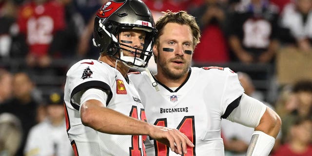 Tom Brady, #12 of the Tampa Bay Buccaneers, talks with Blaine Gabbert, #11, before a game against the Arizona Cardinals at State Farm Stadium on December 25, 2022 in Glendale, Arizona. 