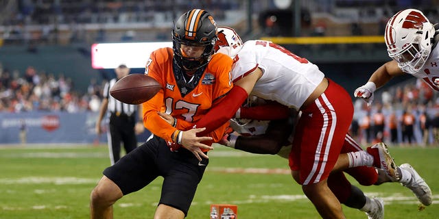 Oklahoma State Cowboys No. 13 quarterback Garret Rangel fumbles the ball out of bounds after being hit by Wisconsin Badgers No. 8 cornerback Avyonne Jones during the second half of the Guaranteed Bowl at Chase Field on December 27, 2022 in Phoenix.