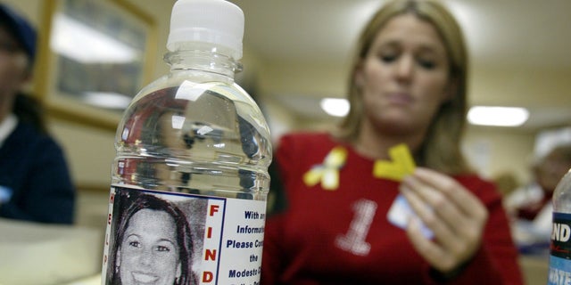 Volunteer Stacey Boyers folds yellow ribbons near a bottle displaying a label with a picture of the missing Laci Peterson Jan. 4, 2003, in Modesto, Calif.