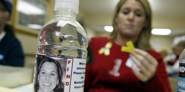 Volunteer Stacey Boyers folds yellow ribbons near a bottle displaying a label with a picture of the missing Laci Peterson Jan. 4, 2003, in Modesto, Calif.