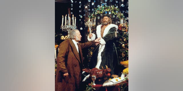 George C. Scott (at left) stars as the stingy businessman Ebenezer Scrooge, and Edward Woodward (at right) is the Ghost of Christmas Present, in "A Christmas Carol," Charles Dickens' classic holiday tale. Originally broadcast on CBS on Dec. 17, 1984. Image dated April 1, 1984. 