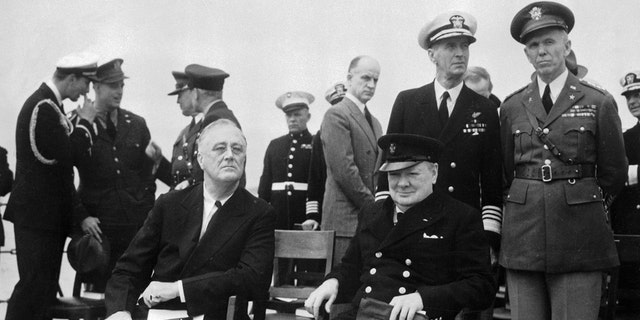 President Roosevelt and Prime Minister Churchill are shown on the big forward deck of H.M.S. Prince of Wales as they relax, chat and breathe a bit of salt air during their epoch-making Atlantic meeting on March 15, 1941. Behind the two at right are: Admiral E.J. King, commander of the U.S. Atlantic Fleet, and Gen. George C. Marshall (far right).
