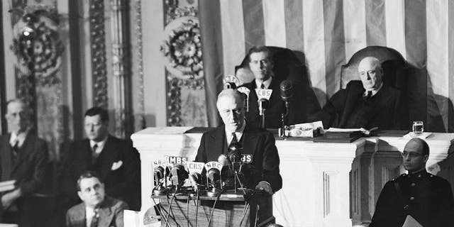 O presidente Franklin D. Roosevelt é retratado durante os momentos dramáticos antes da sessão conjunta do Congresso, em 8 de dezembro de 1941, quando pediu ao Congresso que declarasse guerra contra o Japão por seu "ataque covarde e não provocado". À direita está seu filho, James Roosevelt. Ao fundo estão o vice-presidente Henry A. Wallace (à esquerda) e o presidente da Câmara, Sam Rayburn. Tanto o Senado quanto a Câmara atenderam ao pedido de FDR quase imediatamente. 