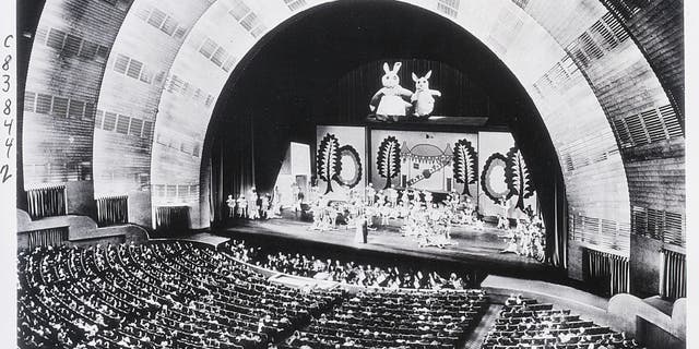New York, New York: This striking photo of the interior of the Radio City Music Hall in Rockefeller Center was taken of the world's largest theater. Presenting an unusual photographic problem, it was made during an actual stage presentation under normal house lighting conditions while an audience of 6,200 persons was watching the finale of one of the great spectacles that have become associated with the name of the place.