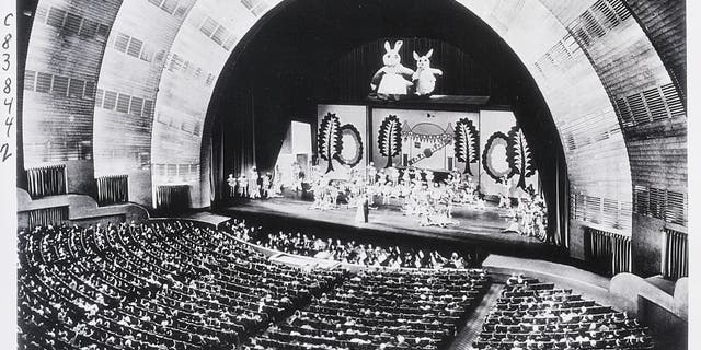 New York, NY: This striking photo of the interior of the Radio City Music Hall in Rockefeller Center is the newest picture to be taken of the world's largest theater. Presenting an unusual photographic problem, it was made during an actual stage presentation under normal house lighting conditions while an audience of 6,200 persons was watching the finale of one of the great spectacles that have become associated with the name of the place.