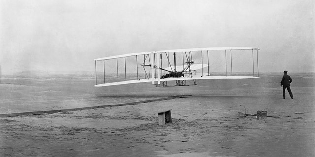 17 दिसंबर, 1903 को ऑरविल राइट के साथ पहला फ़्लायर किल डेविल हिल से उड़ान भरता है, जबकि उसका भाई विल्बर देखता है।