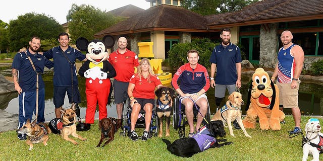 The Service Dogs Of The Invictus Games pose with their owners from left to right Leonard Anderson, August O'Niell, Luc Martin, Christine Gauthier, Jon Flint, Stefan Leroy, Brett Parks at Shades of Green on May 12, 2016 in Lake Buena Vista, Florida.  (Photo by Gustavo Caballero/Getty Images)