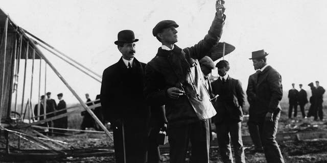 Picture of the Wright Brothers with Orville watching Wilbur take readings outdoors, circa 1908. 