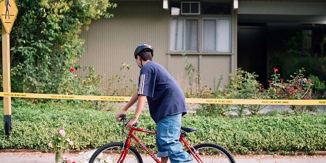 Classmates of Peter Pokhilko rode their bicycles to visit a makeshift memorial in front of the Pokhilko residence on Ferne Avenue in Palo Alto, California, on Sept. 23, 1998. The memorial was left by Peter's classmates the day after his body was found.