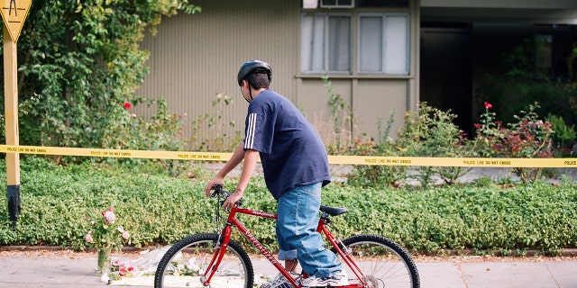 Classmates of Peter Pokhilko rode their bicycles to visit a makeshift memorial in front of the Pokhilko residence on Ferne Avenue in Palo Alto, California, on Sept. 23, 1998. The memorial was left by Peter's classmates the day after his body was found.