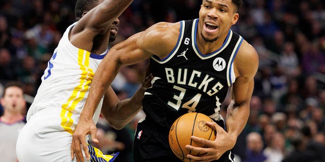 El alero de los Milwaukee Bucks, Giannis Antetokounmpo (34), impulsa la canasta alrededor del alero de los Golden State Warriors, Draymond Green (23), durante el tercer cuarto en el Fiserv Forum el 13 de diciembre de 2022 en Milwaukee.