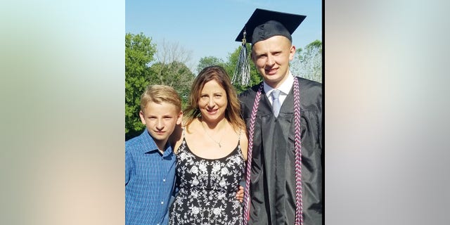 Ken DeLand, an American college student missing in France, is pictured after his high school graduation with his mother, Carol Laws, and younger brother.