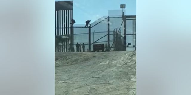 Illegal immigrants are seen climbing over a fence at the U.S.-Mexico border in El Paso, Texas.