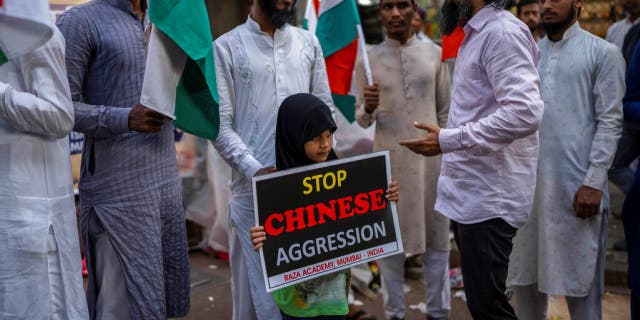 An Indian girl holds a placard during a protest against China in Mumbai, India, Tuesday, Dec. 13, 2022.