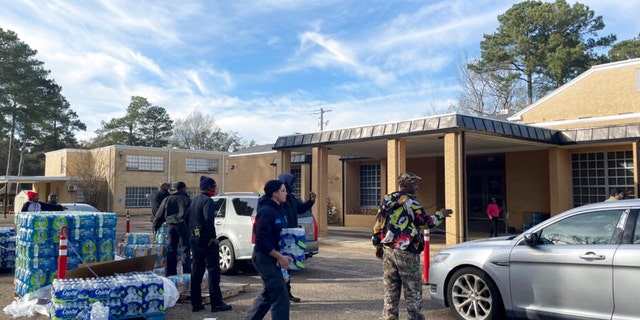 A line of cars meanders past several city blocks as workers from the Rapid Response Coalition of Mississippi hand out bottled water to residents of Jackson, Mississippi, on Tuesday, Dec. 27, 2022.