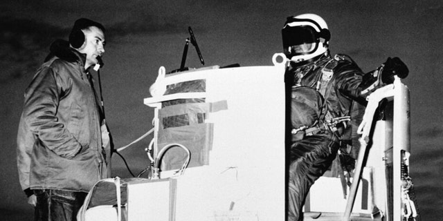 FILE - In this photo provided by the U.S. Air Force, Capt. Joseph Kittinger Jr., director of the aerospace laboratory, sits in the open balloon gondola after his first parachute test jump for Project Excelsior at the Air Force Missile Development Center, N.M. November 16, 1959. The gondola carries him to an altitude of 76,400 feet for his record freefall jump of more than 12 miles.  On the left is David Willard, who designed and developed special equipment for the gondola.