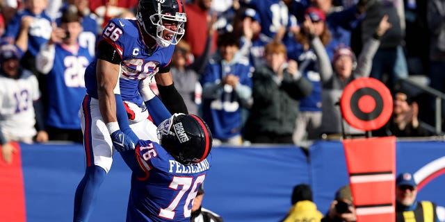 Saquon Barkley #26 celebrates with Jon Feliciano of the New York Giants after scoring a touchdown in the second quarter against the Washington Commanders at MetLife Stadium, Dec. 4, 2022, in East Rutherford, New Jersey.