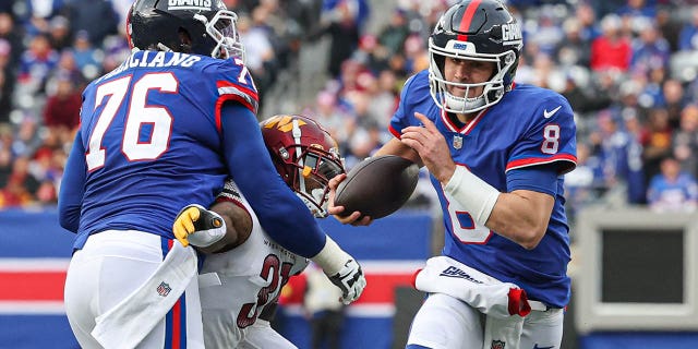 New York Giants quarterback Daniel Jones (8) scrambles as guard Jon Feliciano (76) blocks Washington Commanders safety Kamren Curl during the second half at MetLife Stadium, Dec. 4, 2022, in East Rutherford, New Jersey.