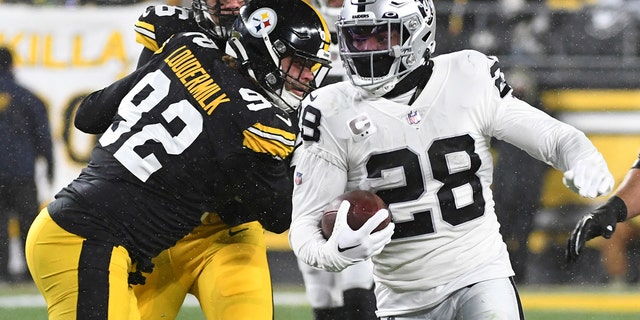Josh Jacobs, 28, runs back for the Las Vegas Raiders carrying the ball during the first half of an NFL football game against the Pittsburgh Steelers in Pittsburgh, Saturday, Dec. 24, 2022. 