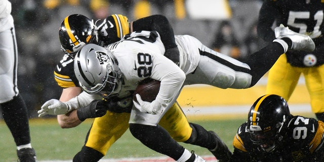 Las Vegas Raiders running back Josh Jacobs, 28, is tackled by Pittsburgh Steelers linebacker Robert Spillane, 41, during the first half of an NFL football game in Pittsburgh on Saturday, Dec. 24, 2022. 