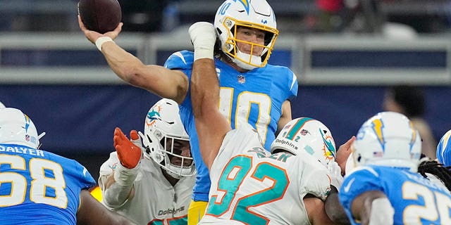 Los Angeles Chargers quarterback Justin Herbert, top, throws under pressure from Miami Dolphins defensive tackle Zach Sieler (92) during the second half of an NFL football game Sunday, Dec. 11, 2022, in Inglewood, Calif. 