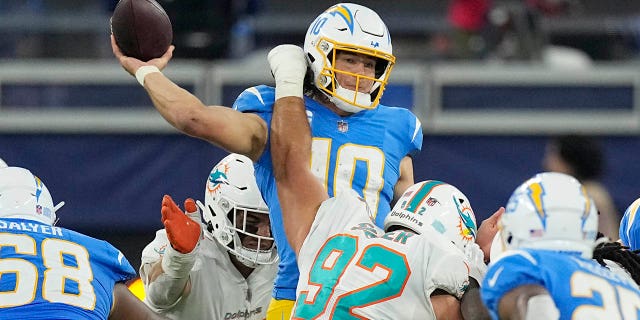 Los Angeles Chargers quarterback Justin Herbert, top, throws under pressure from Miami Dolphins defensive tackle Zach Sieler (92) during the second half of an NFL football game Sunday, Dec. 11, 2022, in Inglewood, Calif. 